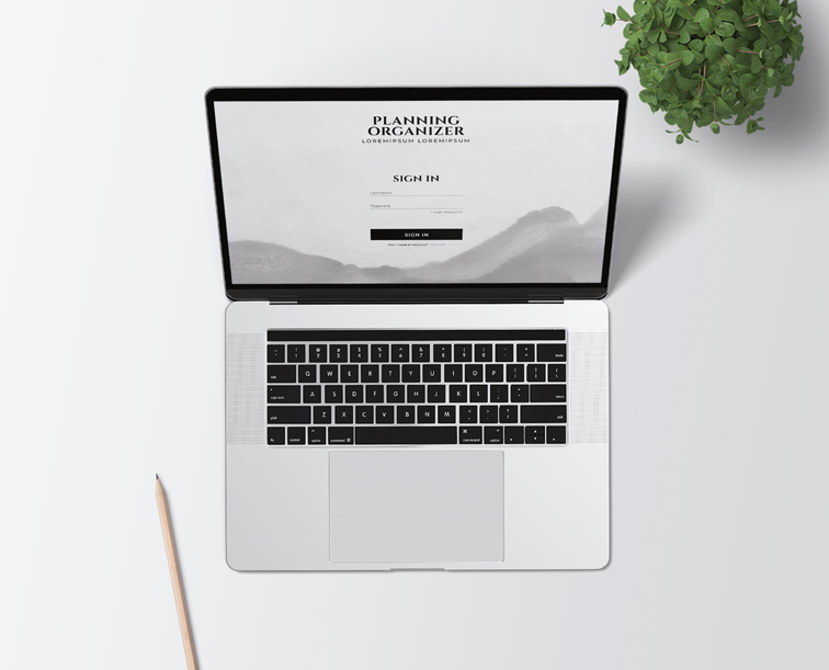 Portátil junto a un lápiz y una planta