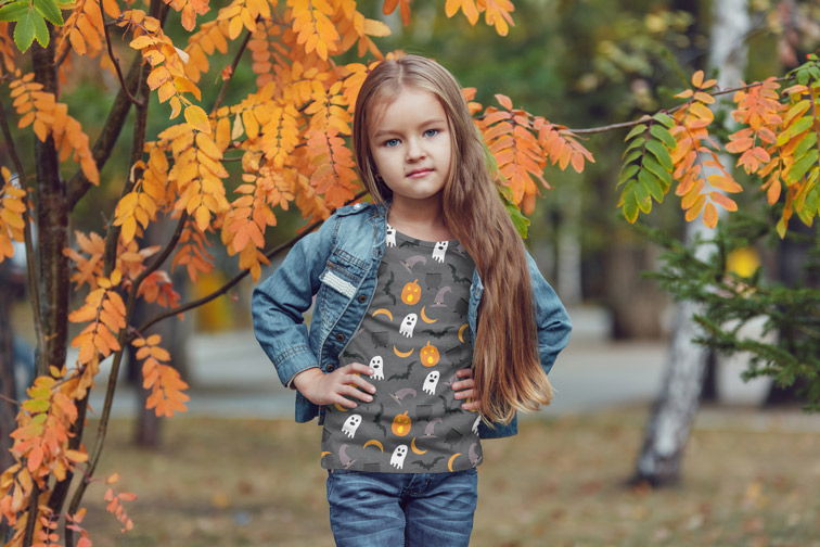 Niña de pie junto a un árbol otoñal