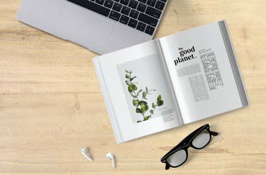 Aufgeschlagenes Buch und AirPods auf einem Schreibtisch