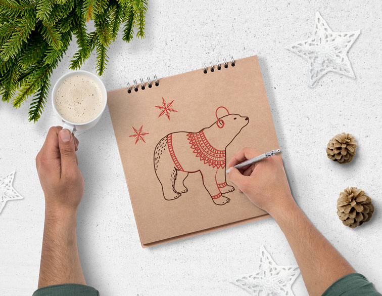 يد على كراسة رسم بجوار تهاني الكريسماس