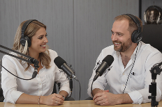 Two podcast hosts in a studio with moody lighting, orange wall and teal accents